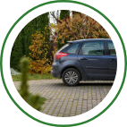 A gray hatchback is parked on a brick driveway. 